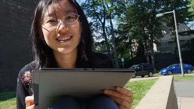 Meng Gu sits outside with a laptop