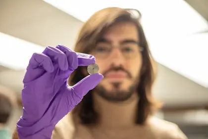Julien Rojas holds up a sample while wearing purple nitrile gloves